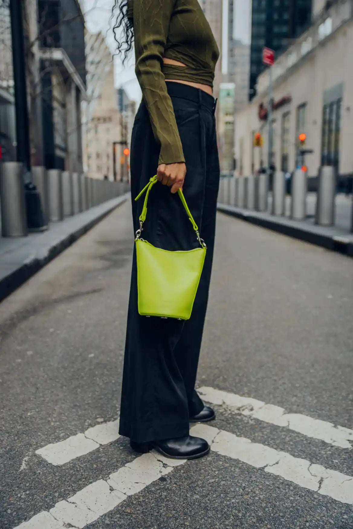 Person holding a bright green handbag on an urban street